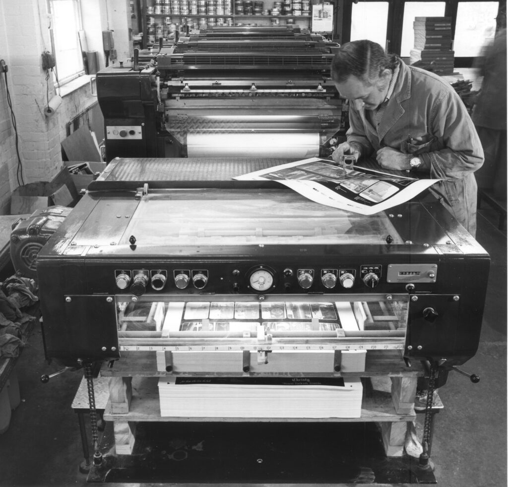 Man at printing press looking at print